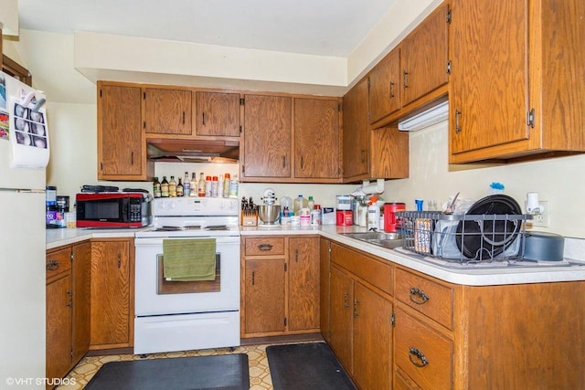 314 E Maple Ave, Beaver Dam, WI 53916 - kitchen featuring white appliances, under cabinet range hood, light countertops, and brown cabinets