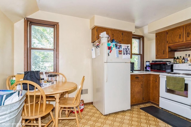 314 E Maple Ave, Beaver Dam, WI 53916 - kitchen with white appliances, under cabinet range hood, brown cabinets, and plenty of natural light