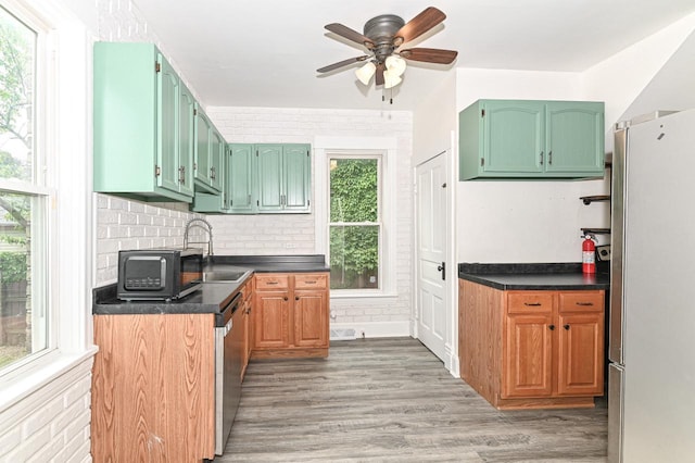 1443 Summit Ave, Racine, WI 53404 - kitchen with appliances with stainless steel finishes, a ceiling fan, dark countertops, light wood-type flooring, and backsplash