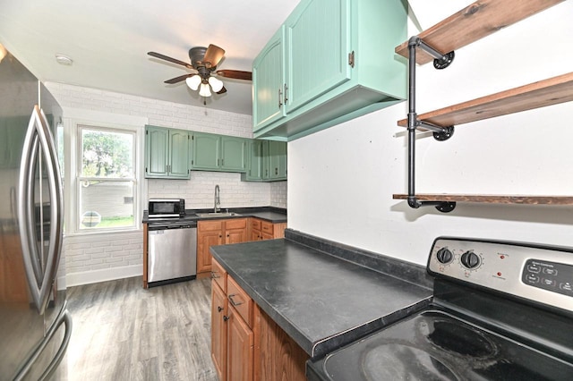 1443 Summit Ave, Racine, WI 53404 - kitchen featuring stainless steel appliances, a ceiling fan, dark countertops, light wood-type flooring, and tasteful backsplash