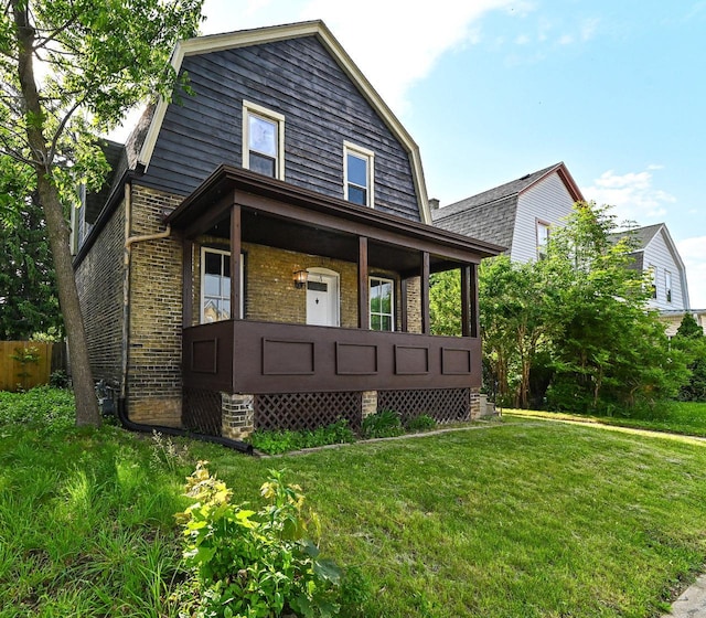 1443 Summit Ave, Racine, WI 53404 - colonial inspired home featuring a porch, a gambrel roof, brick siding, and a front yard