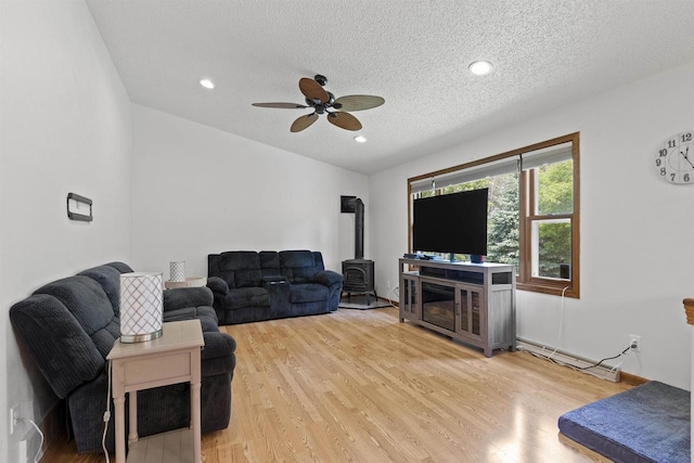 106 Lamine Ln, Combined Locks, WI 54113 - living area featuring a wood stove, ceiling fan, a baseboard radiator, a textured ceiling, and light wood-style flooring