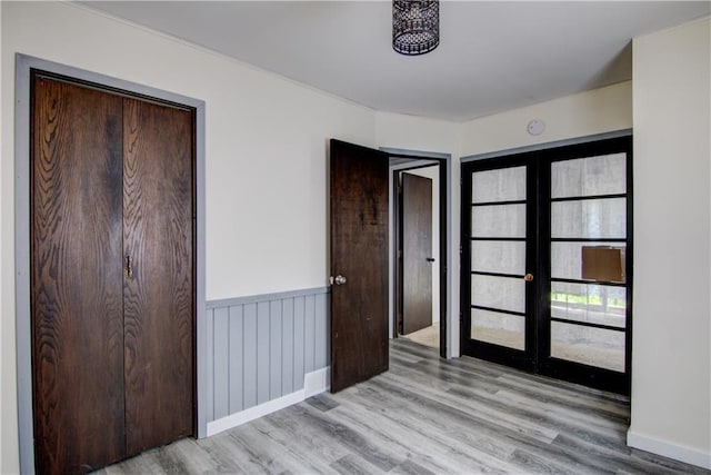 N211 County Road J, Hatfield, WI 54754 - unfurnished bedroom with wood finished floors, french doors, a wainscoted wall, and baseboards