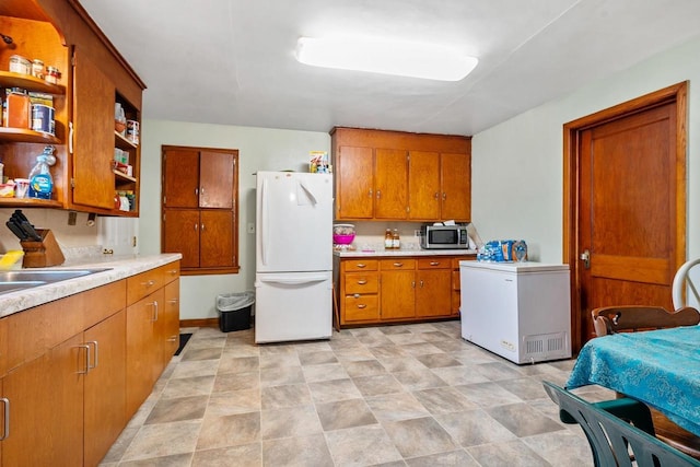 106 S Richmond Ave, Gillett, WI 54124 - kitchen featuring freestanding refrigerator, white refrigerator, stainless steel microwave, open shelves, and brown cabinetry