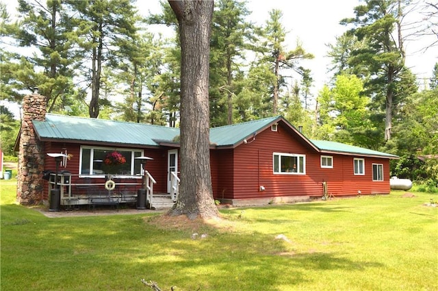 4878N Fur Farm Trl, Winter, WI 54896 - view of front facade featuring a front yard, a chimney, metal roof, and view of wooded area