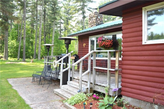 4878N Fur Farm Trl, Winter, WI 54896 - property entrance featuring a deck, faux log siding, metal roof, a yard, and a chimney