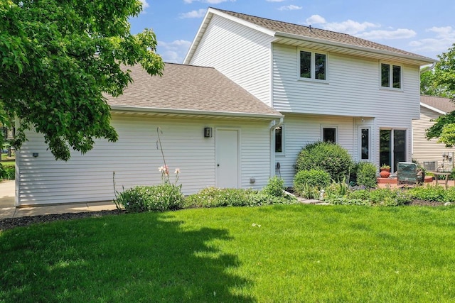 2592 Radinz Rd, Green Bay, WI 54311 - rear view of property featuring a lawn, a shingled roof, and a patio