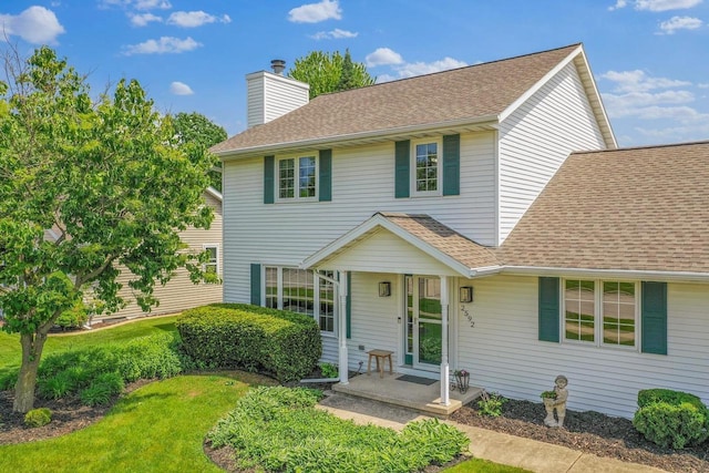 2592 Radinz Rd, Green Bay, WI 54311 - traditional-style house featuring a shingled roof, a chimney, and a front lawn