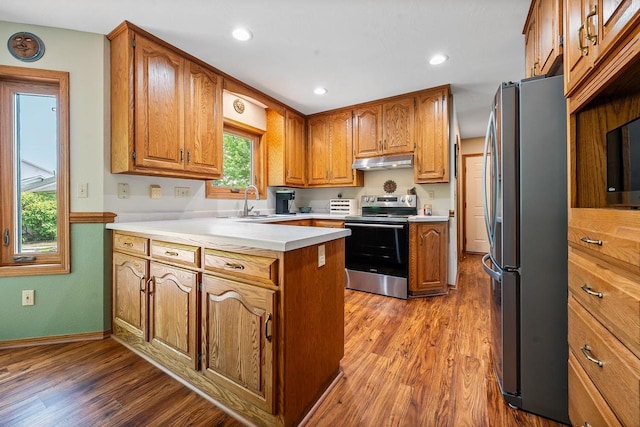 2592 Radinz Rd, Green Bay, WI 54311 - kitchen with stainless steel appliances, under cabinet range hood, a peninsula, brown cabinets, and recessed lighting