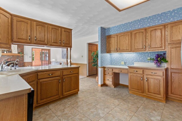 146 Old Orchard Ln, Neenah, WI 54956 - kitchen featuring wallpapered walls, a sink, brown cabinetry, light countertops, and a peninsula