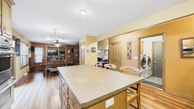 N6464 Canterbury Dr, Fond Du Lac, WI 54937 - kitchen featuring washing machine and clothes dryer, stainless steel appliances, light wood-type flooring, and a kitchen island