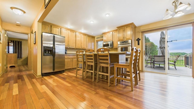N6464 Canterbury Dr, Fond Du Lac, WI 54937 - kitchen with appliances with stainless steel finishes, light wood-style flooring, and a breakfast bar