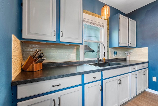 1212 N Leminwah St, Appleton, WI 54911 - kitchen with a sink, dark countertops, decorative backsplash, white cabinetry, and light wood finished floors