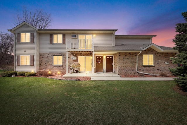 2020 Meadow Ct Unit 2, West Bend, WI 53095 - view of front facade with a balcony, brick siding, a front yard, and a patio