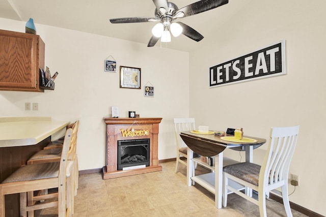 2020 Meadow Ct Unit 2, West Bend, WI 53095 - dining area with a fireplace with raised hearth, a ceiling fan, and baseboards