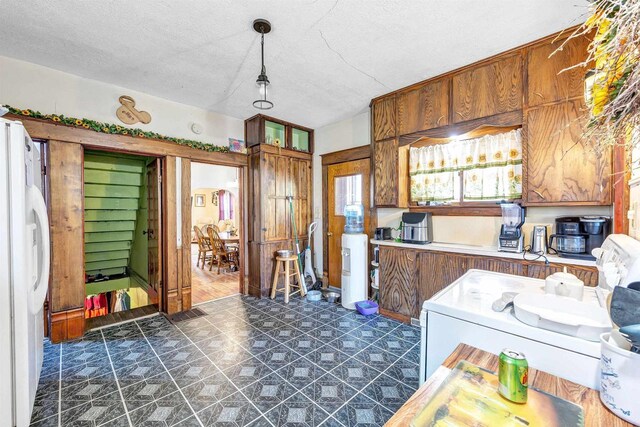 823 N Main St, Marion, WI 54950 - kitchen featuring freestanding refrigerator, washer / clothes dryer, brown cabinets, a textured ceiling, and light countertops