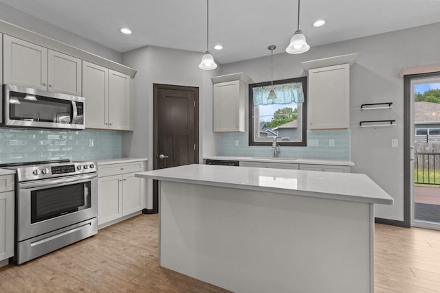 W6008 Zach St, Menasha, WI 54952 - kitchen with stainless steel appliances, a sink, light countertops, light wood-style flooring, and hanging light fixtures