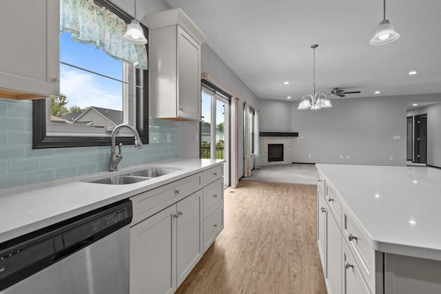 W6008 Zach St, Menasha, WI 54952 - kitchen featuring stainless steel dishwasher, a sink, open floor plan, a stone fireplace, and light countertops