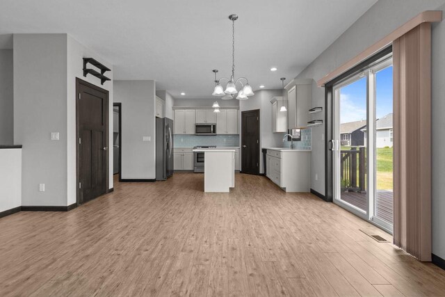 W6008 Zach St, Menasha, WI 54952 - kitchen featuring appliances with stainless steel finishes, a chandelier, light countertops, light wood-style flooring, and decorative backsplash