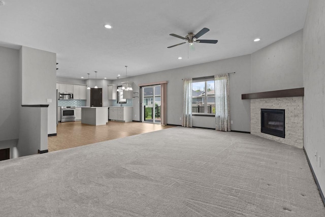 W6008 Zach St, Menasha, WI 54952 - unfurnished living room with light carpet, recessed lighting, a ceiling fan, a fireplace, and a chandelier