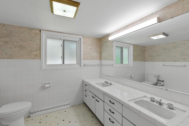 2373 State Road 33, Saukville, WI 53080 - full bath featuring toilet, a baseboard heating unit, tile walls, double vanity, and healthy amount of natural light