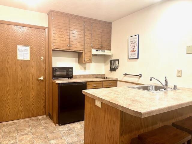 7741 State Highway 42 Unit 105, Egg Harbor, WI 54209 - kitchen with black appliances, under cabinet range hood, a peninsula, a sink, and a kitchen bar