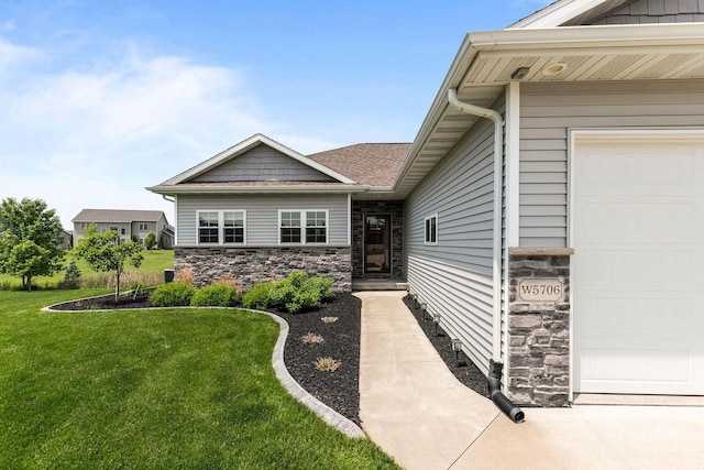 W5706 Mase Ct, Appleton, WI 54915 - view of exterior entry featuring a garage, stone siding, a yard, and a shingled roof