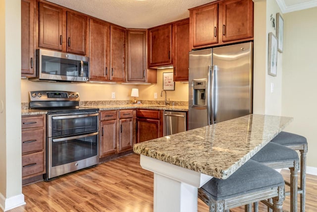1660 N Prospect Ave Unit 611, Milwaukee, WI 53202 - kitchen featuring stainless steel appliances, light wood-style floors, a peninsula, light stone counters, and ornamental molding