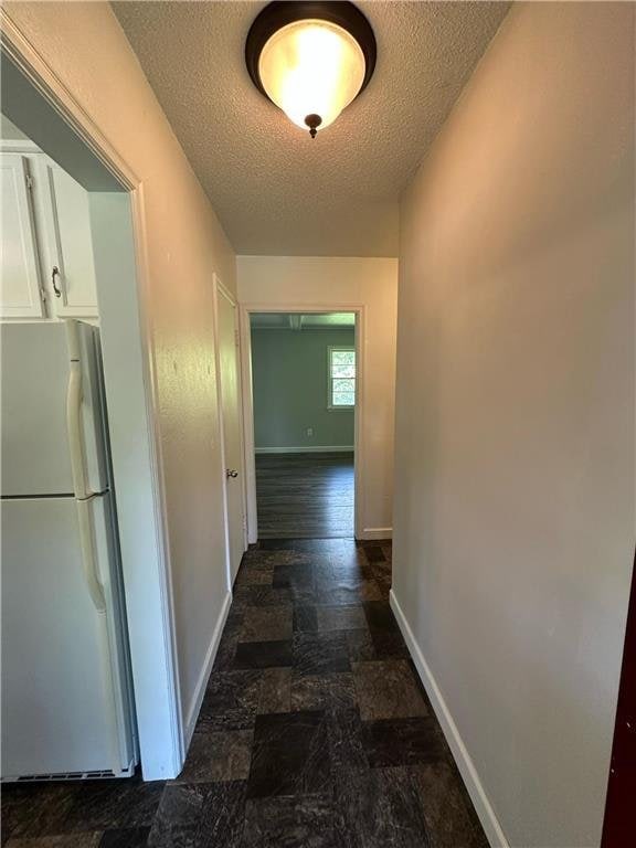 332 E Pleasant Ave, Ellsworth, WI 54011 - hallway featuring a textured ceiling, baseboards, and dark stone finish flooring