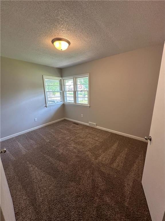 332 E Pleasant Ave, Ellsworth, WI 54011 - spare room featuring dark colored carpet, a textured ceiling, and baseboards