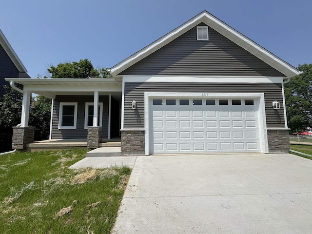 1511 16th Ave, Monroe, WI 53566 - view of front of home with concrete driveway, stone siding, a garage, and a porch