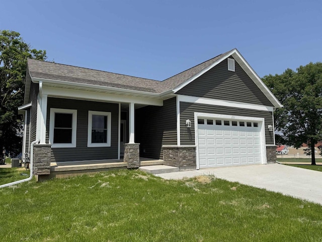 1511 16th Ave, Monroe, WI 53566 - view of front facade featuring stone siding, concrete driveway, a porch, and a front yard