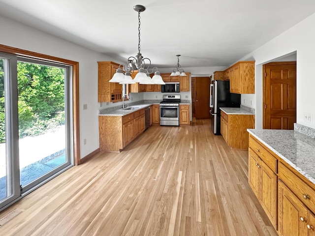 N49W31242 Old Steeple Rd, Hartland, WI 53029 - kitchen featuring stainless steel appliances, a sink, light wood finished floors, brown cabinets, and a chandelier