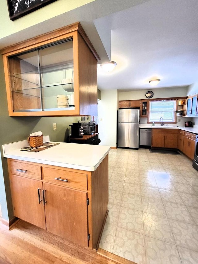 3843 S 95th St, Milwaukee, WI 53228 - kitchen featuring appliances with stainless steel finishes, light countertops, glass insert cabinets, a sink, and brown cabinetry