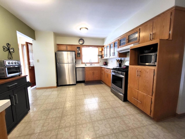 3843 S 95th St, Milwaukee, WI 53228 - kitchen featuring appliances with stainless steel finishes, a sink, light countertops, glass insert cabinets, and under cabinet range hood