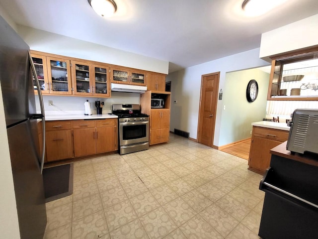 3843 S 95th St, Milwaukee, WI 53228 - kitchen with stainless steel appliances, brown cabinets, under cabinet range hood, light countertops, and glass insert cabinets