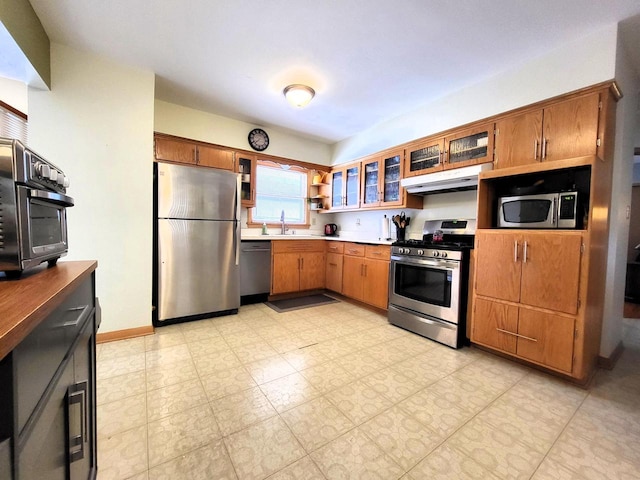 3843 S 95th St, Milwaukee, WI 53228 - kitchen featuring appliances with stainless steel finishes, under cabinet range hood, brown cabinets, and a sink