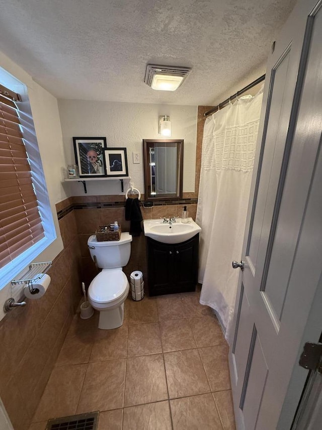 2143 Clark St, Mount Pleasant, WI 53403 - bathroom featuring tile walls, toilet, a textured ceiling, vanity, and tile patterned flooring