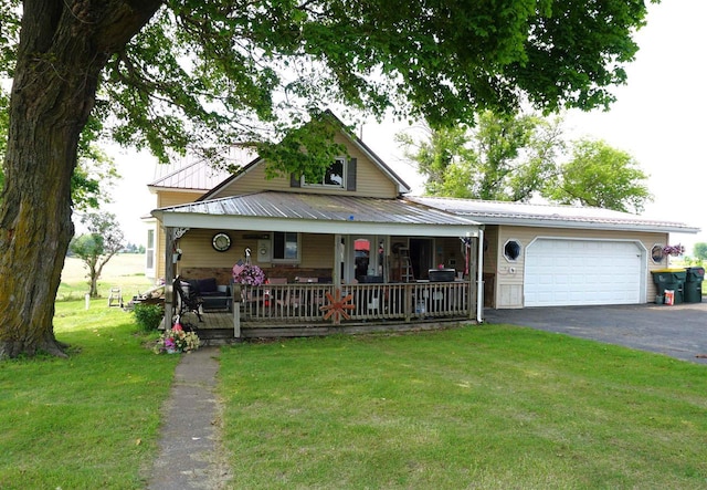 109 N Water St, Eastman, WI 54626 - view of front of house featuring asphalt driveway, a porch, a front yard, a garage, and metal roof