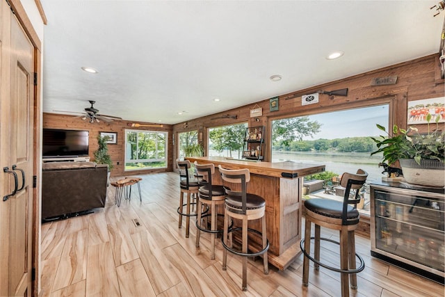 5420 W Peninsula Dr, Waterford, WI 53185 - indoor dry bar with wood walls, wine cooler, light wood-style flooring, recessed lighting, and a ceiling fan