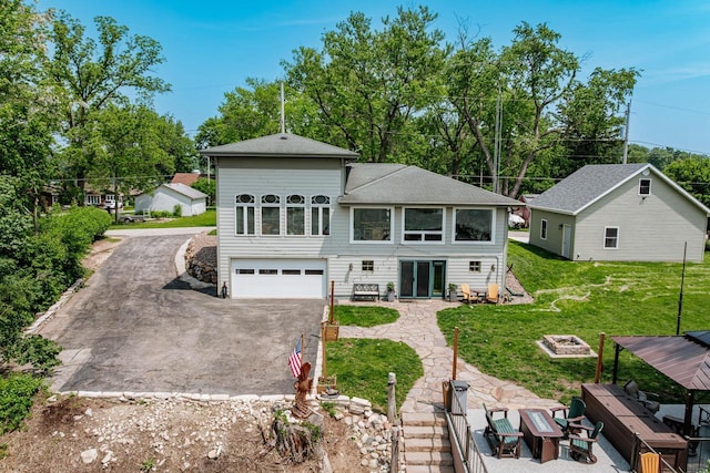 5420 W Peninsula Dr, Waterford, WI 53185 - rear view of house with asphalt driveway, a fire pit, an attached garage, a lawn, and a shingled roof