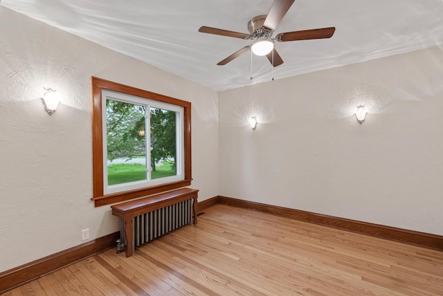 4438 County Road H Prt, Washington, WI 53074 - empty room featuring radiator heating unit, light wood finished floors, a ceiling fan, baseboards, and a textured wall