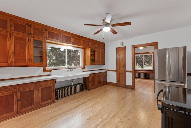 4438 County Road H Prt, Washington, WI 53074 - kitchen featuring radiator heating unit, freestanding refrigerator, brown cabinetry, and plenty of natural light