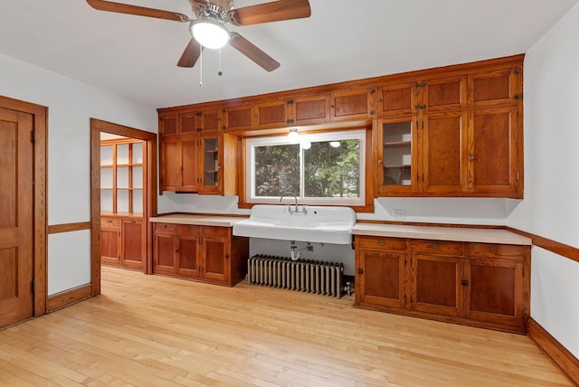 4438 County Road H Prt, Washington, WI 53074 - kitchen with radiator heating unit, brown cabinets, a sink, and light wood finished floors