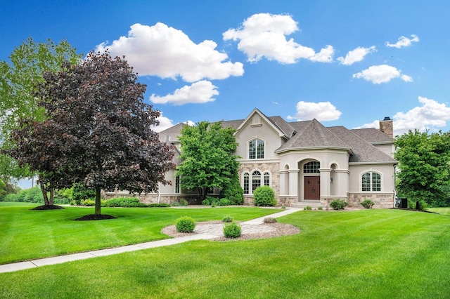 1252 Mary Hill Cir, Hartland, WI 53029 - french country style house featuring stucco siding, stone siding, a front yard, and a chimney