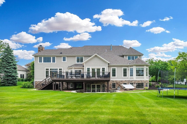 1252 Mary Hill Cir, Hartland, WI 53029 - back of property with a trampoline, a deck, stairs, and a yard