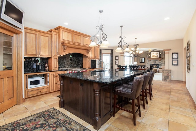 1252 Mary Hill Cir, Hartland, WI 53029 - kitchen with backsplash, white microwave, a sink, an island with sink, and a chandelier