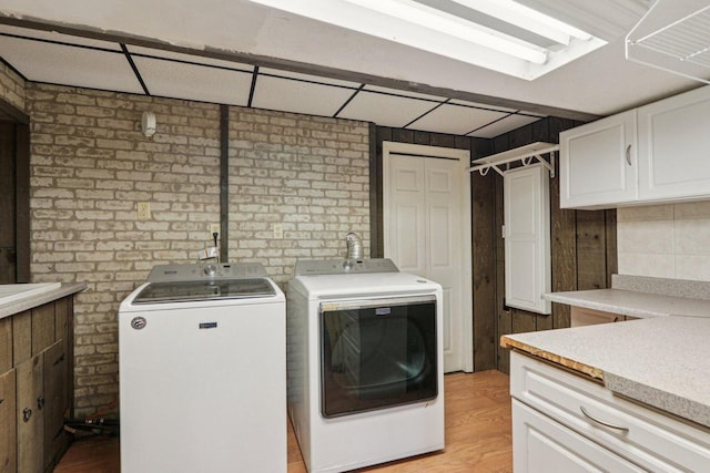 8845 388th Ave, Burlington, WI 53105 - laundry room with cabinet space, separate washer and dryer, light wood-type flooring, and brick wall