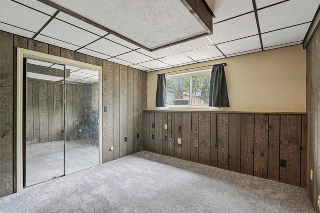 8845 388th Ave, Burlington, WI 53105 - unfurnished bedroom featuring wooden walls, carpet flooring, a drop ceiling, a closet, and wainscoting