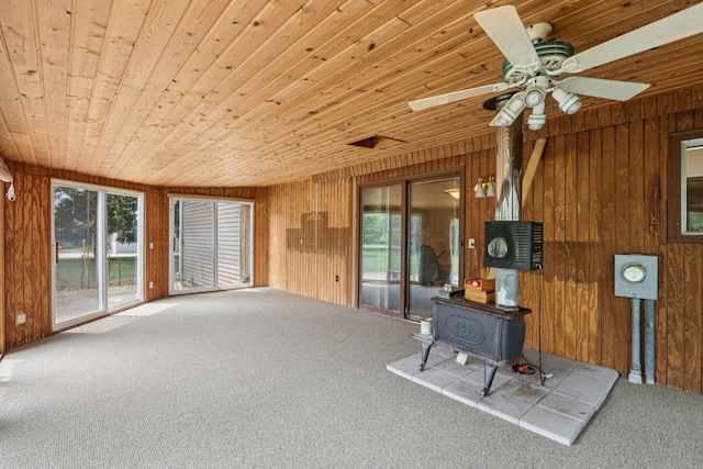 8845 388th Ave, Burlington, WI 53105 - unfurnished living room with carpet flooring, wooden walls, wooden ceiling, a wood stove, and ceiling fan